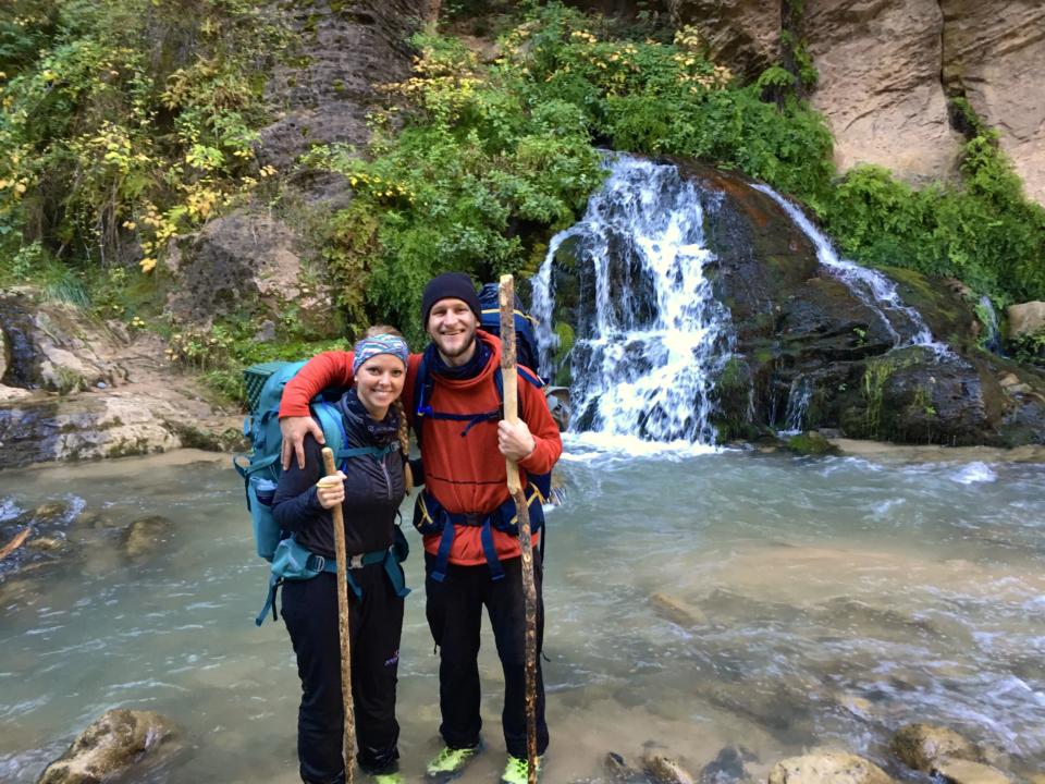 Jake and Emily standing in front of Big Springs with their backpacking gear.