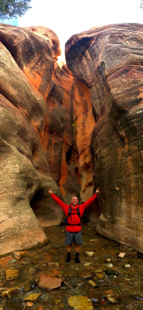 Jake with his hands up in the middle of the narrow canyon at Kanarra Creek