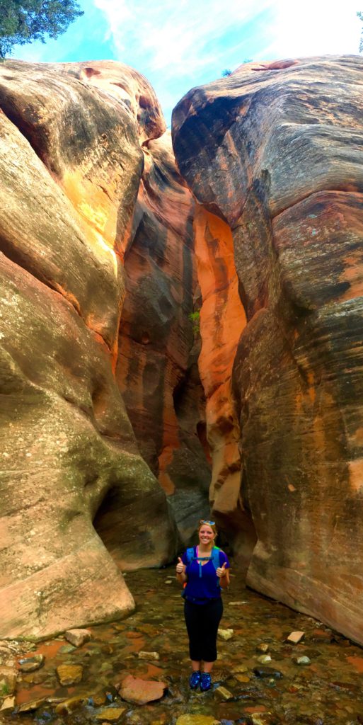 Emily with his hands up in the middle of the narrow canyon at Kanarra Creek