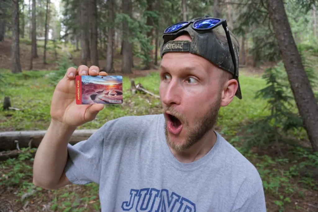 a guy holding a National Parks Pass with a shocked face, showing a great gift idea for hikers and backpackers