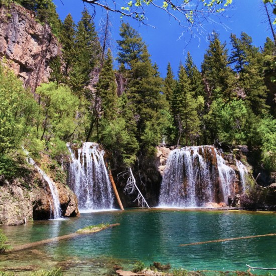 blue-green water with a waterfall flowing into it, making it one of the best hikes in colorado