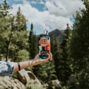 An arm holding a nalgene with nature in the background