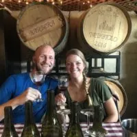 a couple smiling in front of wine barrels at a Harvest Hosts Location