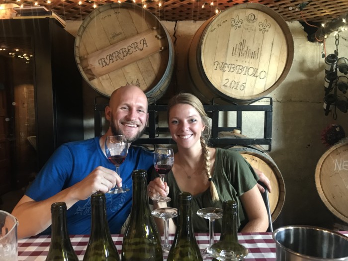 a couple smiling in front of wine barrels at a Harvest Hosts Location