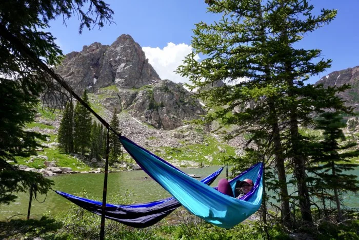 a girl laying in a hammock with an apline lake in the distance, showing one of the best gift ideas for hikers and backpackers