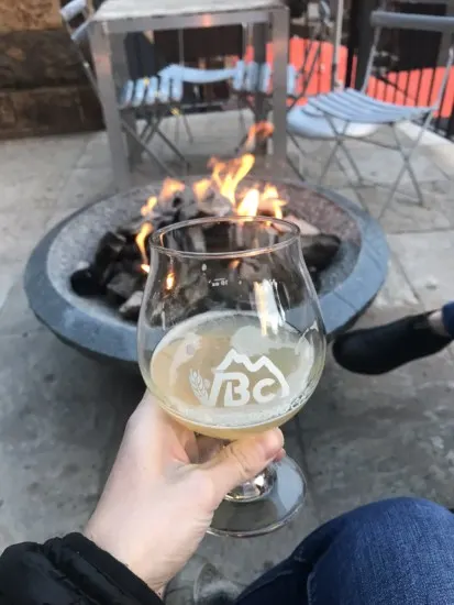 holding a local beer from Vail Brewing Company in front of a fire which is one of the best things to do in vail in summer