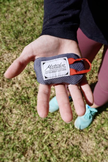 a Matador pocket blanket in the palm of a hand showing its small size and how its a great gift idea for hikers and backpackers