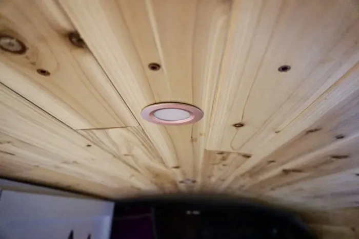 A recessed 12v light installed in a campervan cedar ceiling