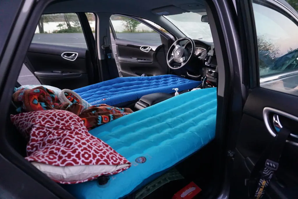 A car camping sleep setup for two people in a sedan