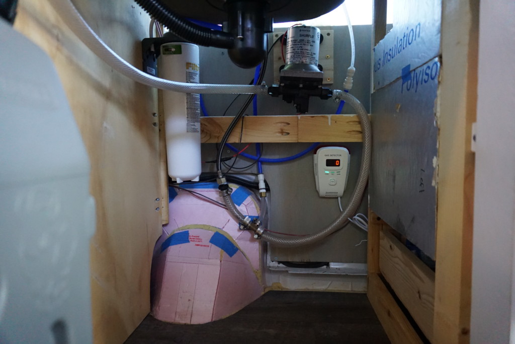 Campervan plumbing underneath with water filter and electric pump