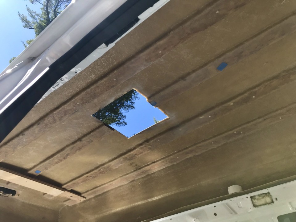A fiberglass van roof with wooden ribs and a hole cut for fan installation