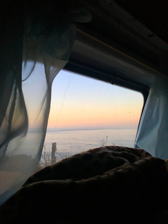 Car window with curtains looking out over the ocean