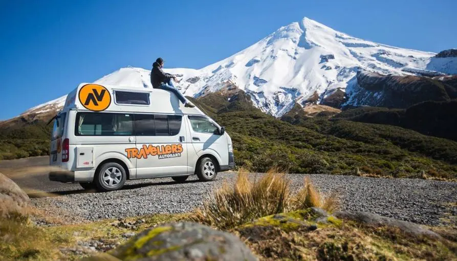 A traveller's Autobarn van is from of snowcapped mountains in New Zealand