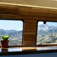 Campervan kitchen with a snake plant on the counter and mountains in the background