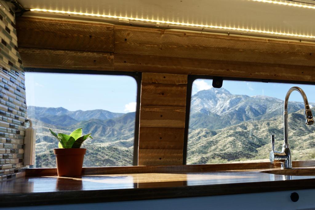 Campervan kitchen with a snake plant on the counter and mountains in the background