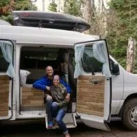 Jake and Emily living vanlife on the stoop of their campervan