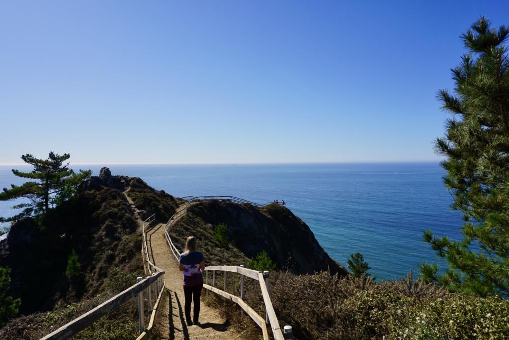 Emily walking on the Muir Beach Overlook which have cliffs on both sides and a great view of the Pacific Ocean