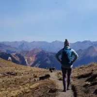 Emily hiking back down Columbine Lake Trail with red mountain peaks in the distance