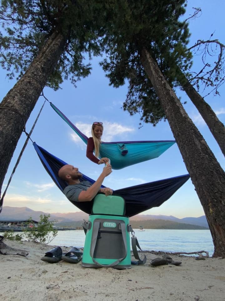 jake and emily hanging in hammocks from a tree with the RTIC cooler, which makes a great van life gift