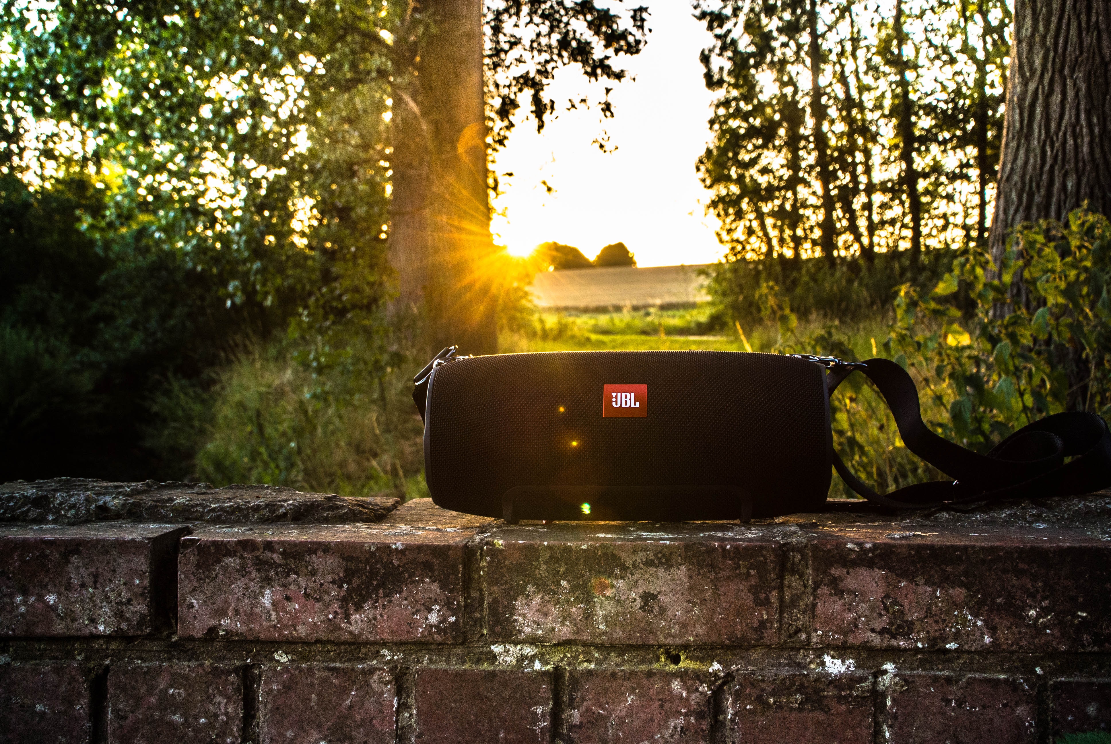 JBL speaker sitting on a brick wall with the sun shining through