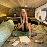 Emily calculating our vanlife monthly expenses on the bed of our campervan