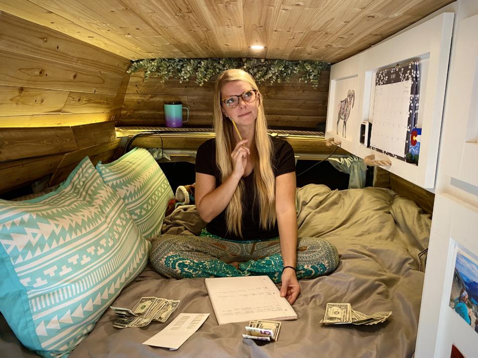 Emily calculating our vanlife monthly expenses on the bed of our campervan