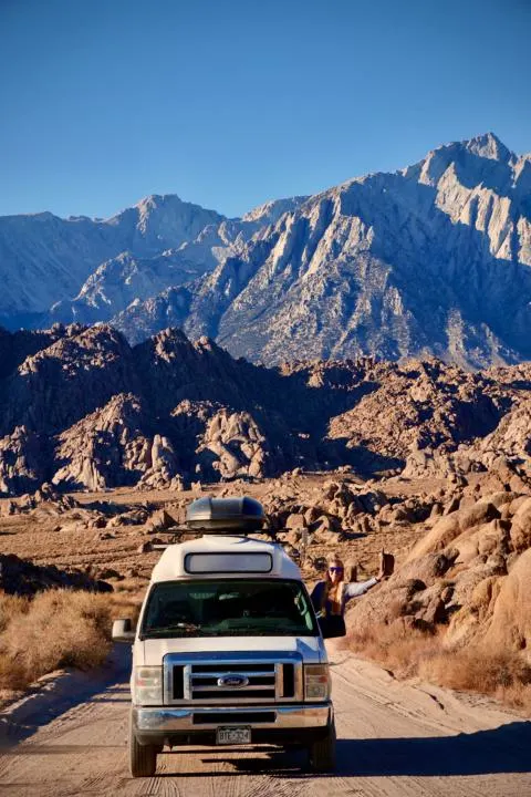 a girl hanging out her camper van window with the Famous Shot At Movie Road in Alabama Hills