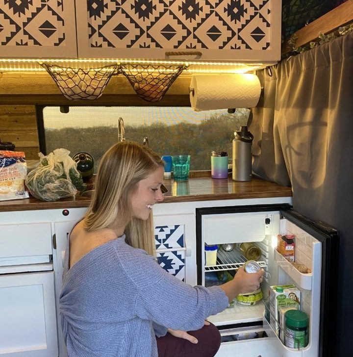 Emily grabbing a beer from one of the best fridges for campervans