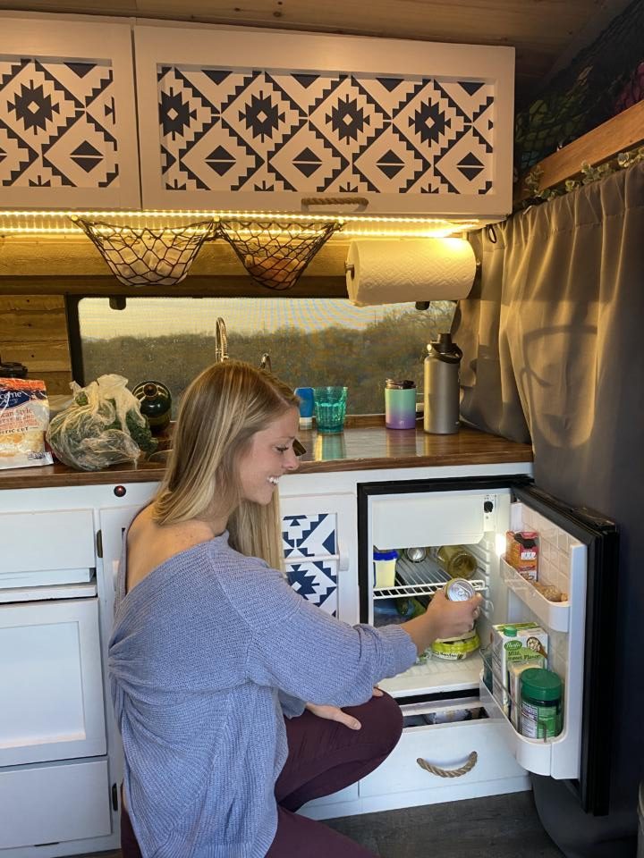 Emily grabbing a beer from one of the best fridges for campervans