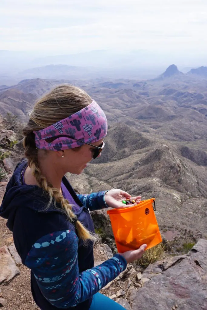 emily eating a handful of trail mix along a hike out of the ust reusable snack bag