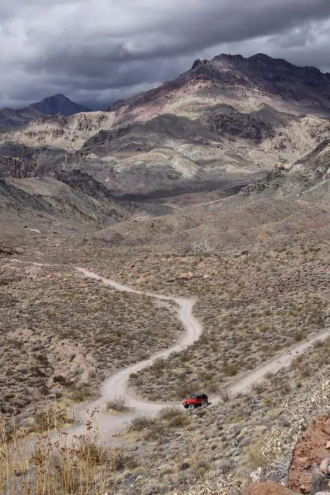 A red Jeep driving down Red Pass towards Leadfield