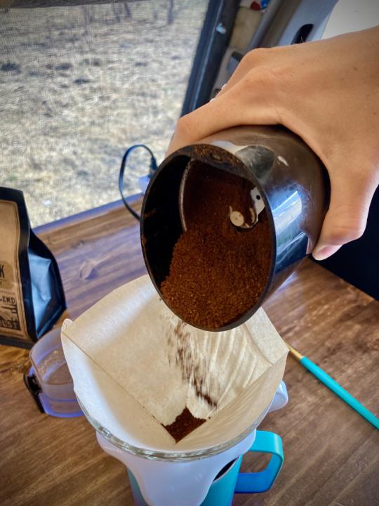 pouring the grounded coffee grounds into the filter