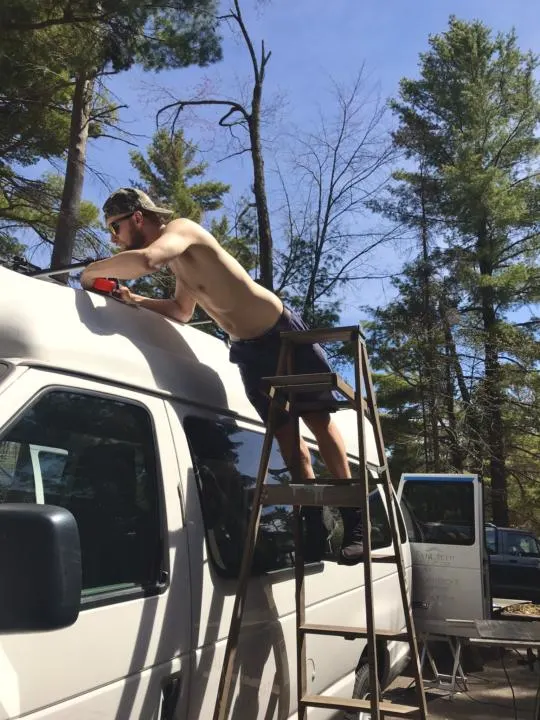 Jake measuring and planning to mount a ski cargo box on fiberglass hightop camper van.