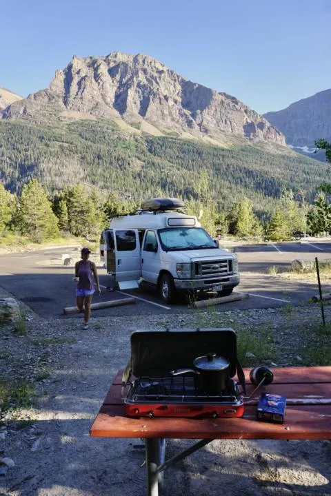 Making pasta salad outside the campervan to stay cool in summer vanlife in glacier