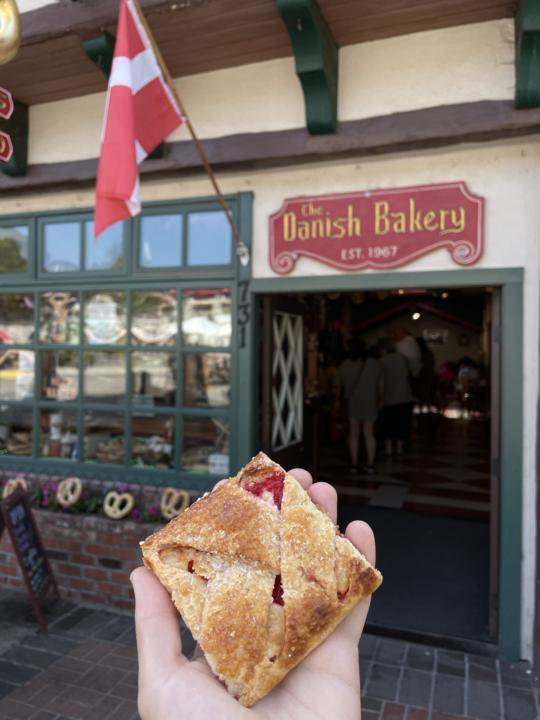 A hand holding a pastry in front of the Danish Bakery in Leavenworth Washington