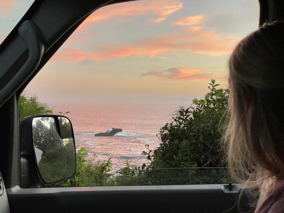 Emily looking out the camper van window at a sunset