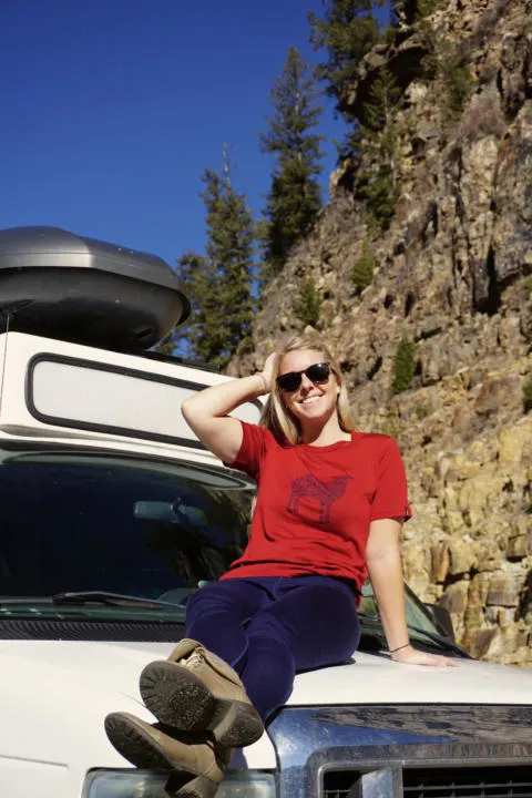 Emily sitting on a camper van wearing Isobaa Merino Wool which is the perfect items for vanlifers