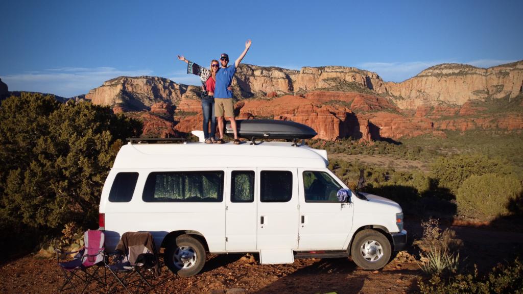 Jake & Emily standing on their camper van showing off one of the best free campsites in Sedona, AZ