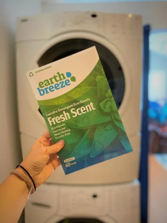 Holding Earth Breeze eco-sheets in front of a laundry machine