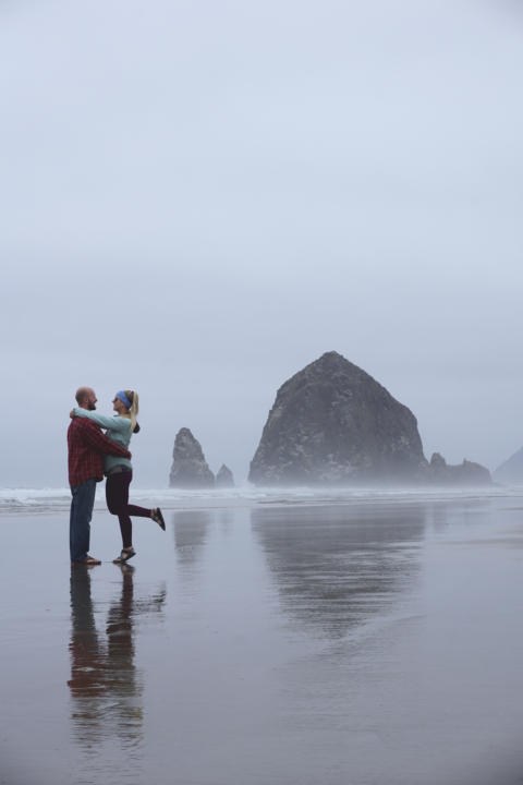 Jake and Em striking a pose in front of Haystack Rock atCannon Beach which is one of the best stops along this Oregon Coast Road Trip