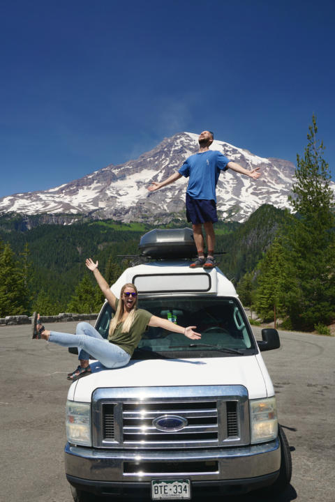 Jake and Emily standing on a van in front of Mount Rainier, which is an easy viewpoint on a Washington Road Trip
