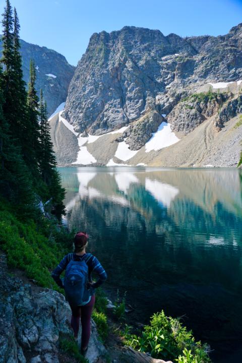 along a washington road trip through the North Cascades National Park, Emily sits along the Blue Lake edge to look onto the beautiful mountain peaks