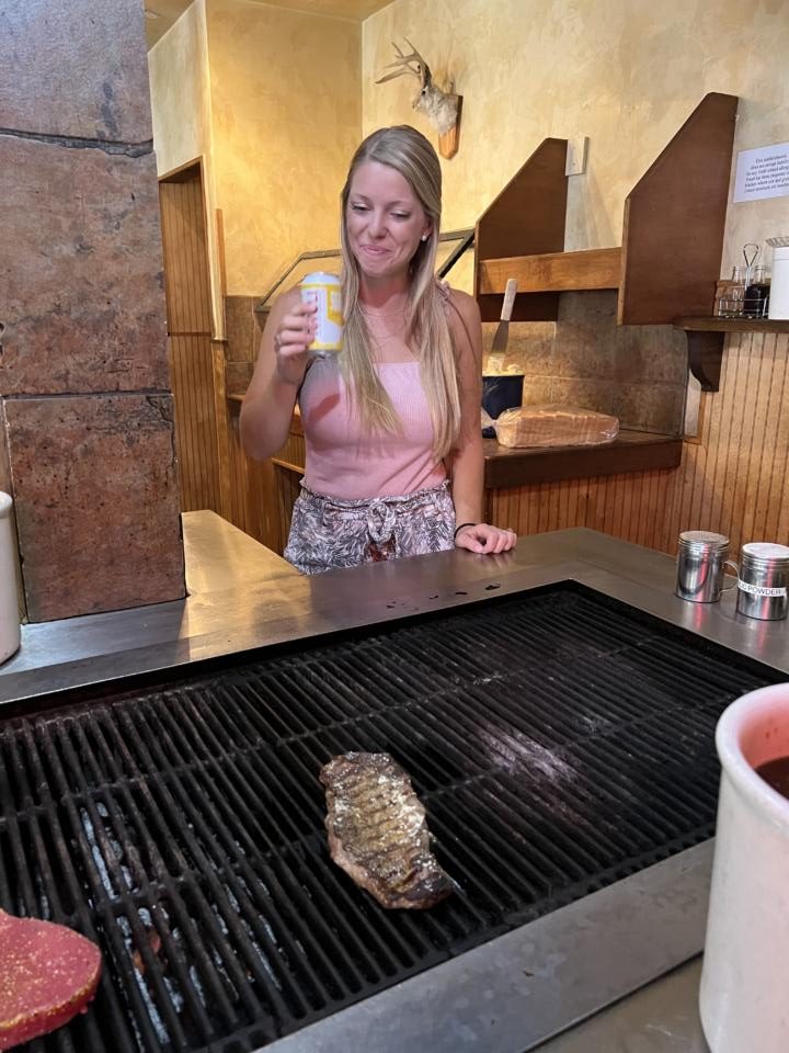 Emily enjoying a beer while cooking her own steak at the Minturn Country Club.