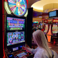 Emily playing a Wheel Of Fortune slot machine on the Sky Ute Casino Floor.