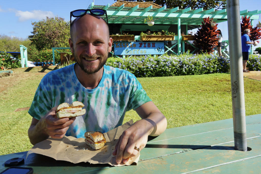 a guy holding a breakfast sandwich from Little Fish Coffee