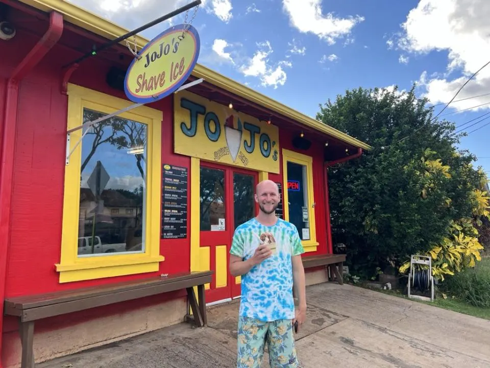Guy holding shaved ice in front of Jojo's Shave Ice - One of the best restaurants in Kauai for shaved ice