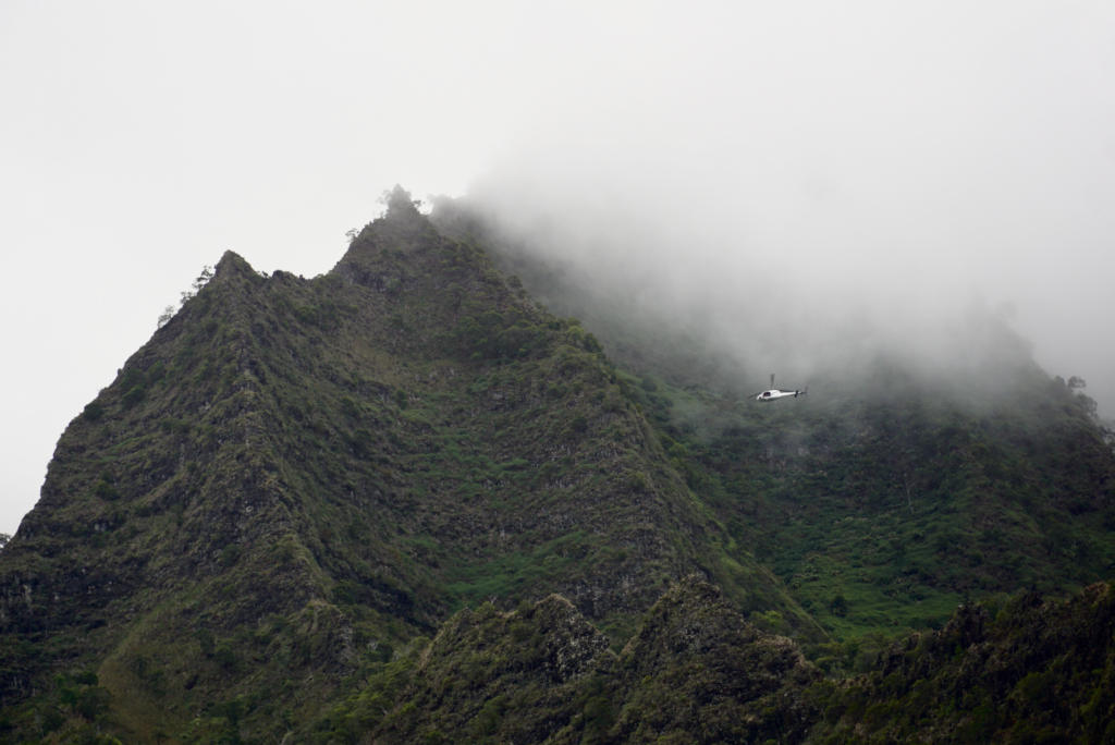 Helicopter flying above Napali Coast through cloudy weather