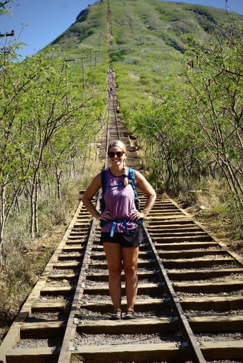 a girl posing on the tramway tracks with arms on hips at Koko Head Crater which is one of the best hikes in Oahu