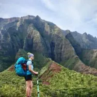 a girl standing in front of the Napali Coast which represents one of the best hikes in Kauai