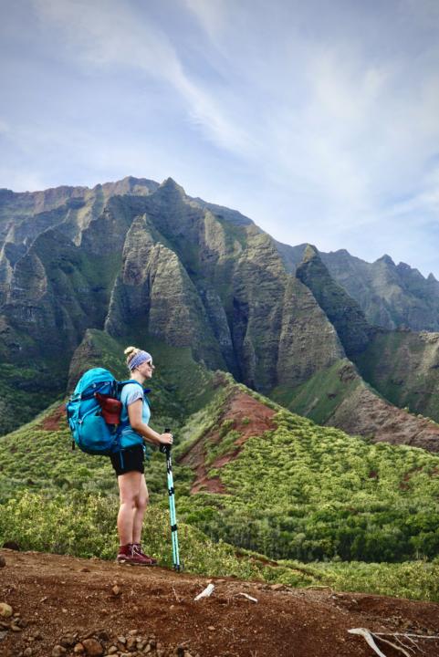a girl standing in front of the Napali Coast which represents one of the best hikes in Kauai